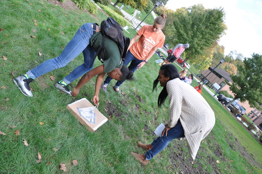 students bending over on lawn