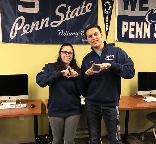 Students standing in front of Penn State Flag