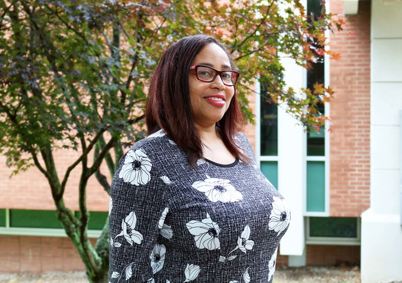 woman wearing glasses smiling in front of a tree