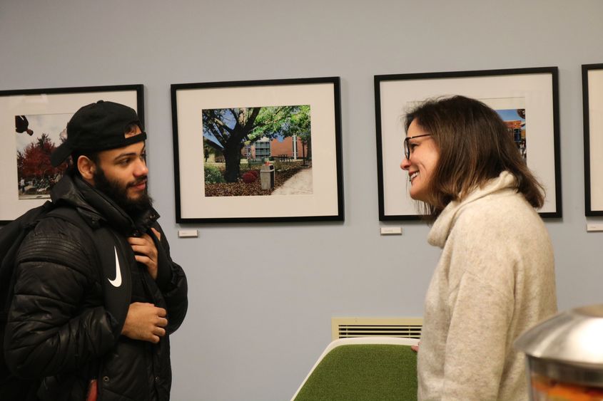 Chancellor Jacqueline Edmondson talking to student about their photo that is hanging on the wall behind them.