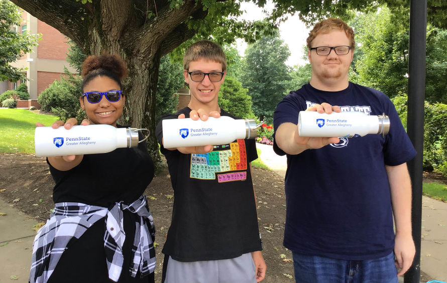 Three students holding white water bottles displaying Greater Allegheny Logos
