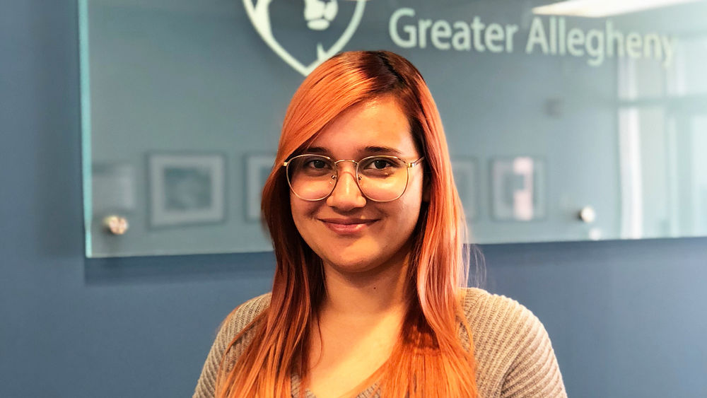 Student Yadeiliz Mari smiling standing in front of Penn State Greater Allegheny Logo