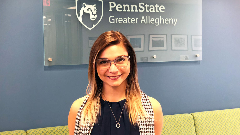 Exchange student Amanda Diana in front of the Penn State Greater Allegheny Logo.