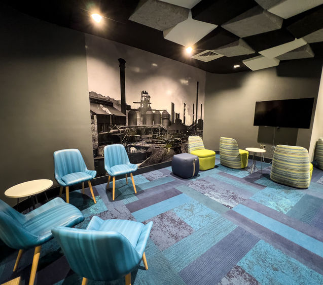 Collaborative space with chairs, tables, and a giant piece of art on the way.
