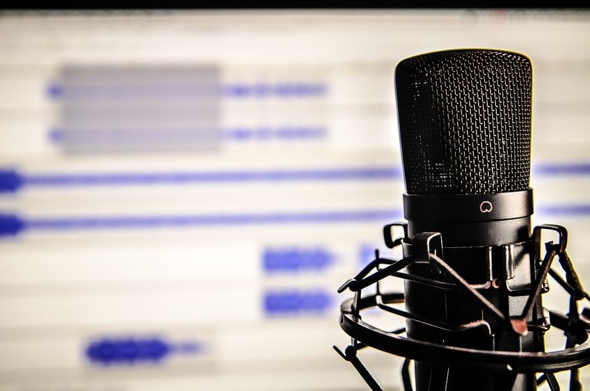 A microphone rests in front of a blurred, white computer screen