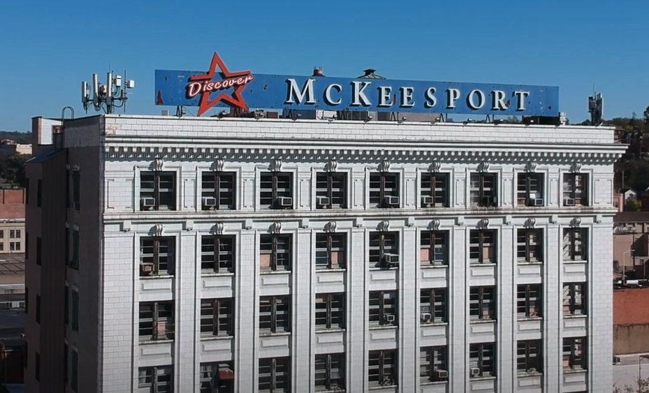 Building with a sign on the roof that reads Mckessport. 
